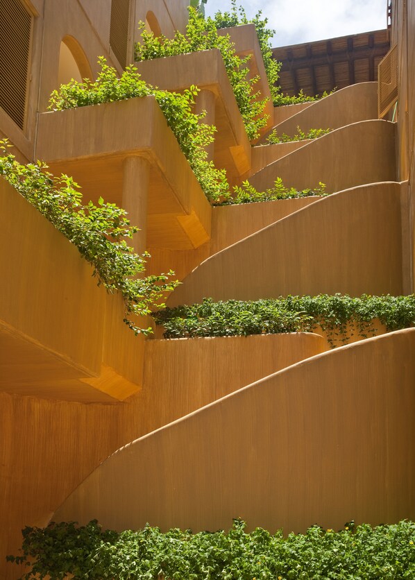 Un bâtiment moderne doté de balcons aux lignes courbes et agrémenté de plantes vertes.