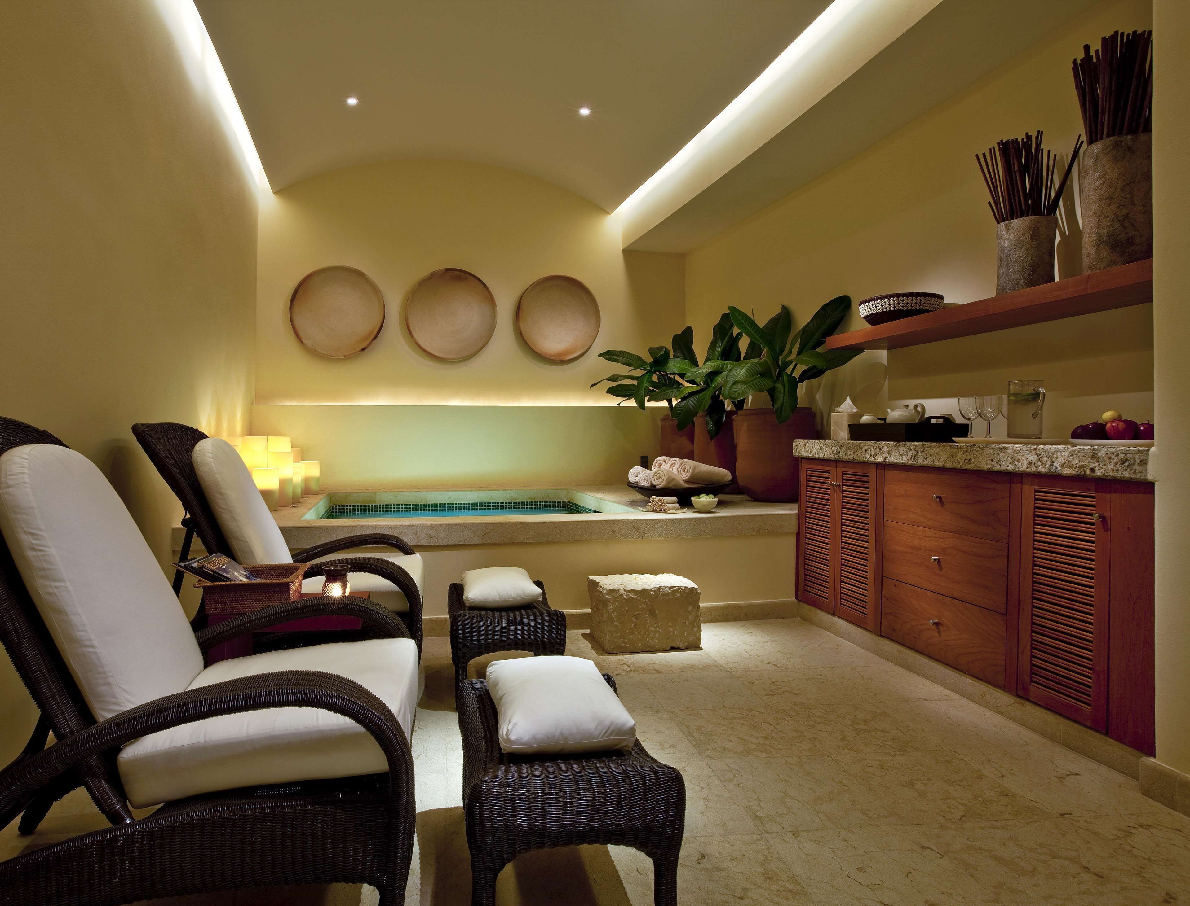 A spa area with wicker chairs, a small pool, and a wooden cabinet with kitchen items.