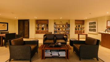 A living room with two brown leather sofas, a wooden coffee table, and a bookshelf filled with books and decorative items.