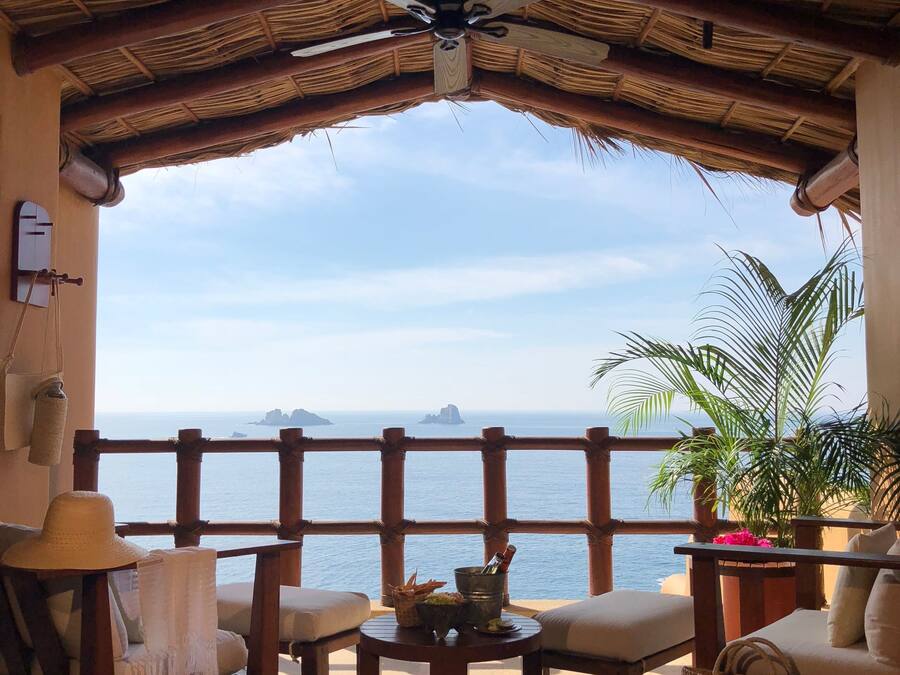 Un rincón tranquilo con techo de paja, muebles de madera y vista al mar.