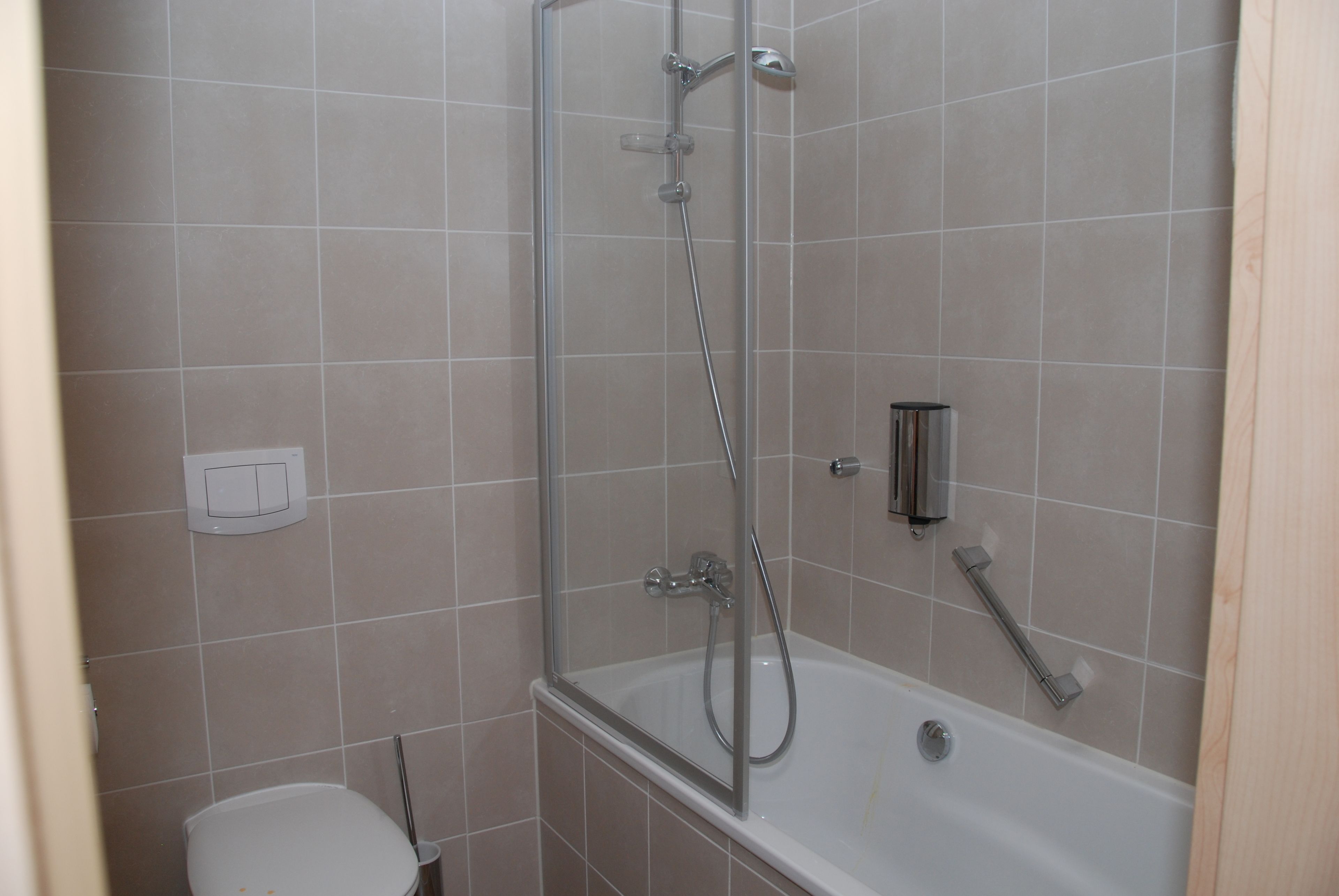 Een badkamer met een douche, toilet en bad.