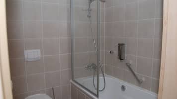 Een badkamer met een douche, toilet en bad.