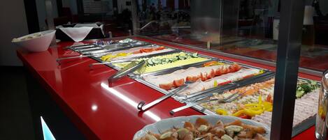 A buffet with various food items, including salmon, vegetables, and other dishes.