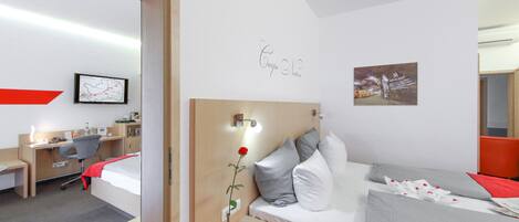 Habitación de hotel con cama, mesita de noche, escritorio y silla. Se observa un mapa en la pared y un cuadro enmarcado.