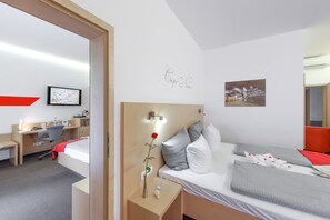 Habitación de hotel con cama, mesita de noche, escritorio y silla. Se observa un mapa en la pared y un cuadro enmarcado.
