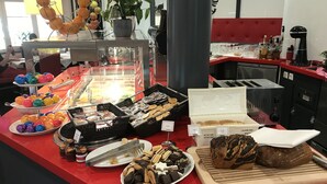 Un mostrador de buffet con diversos alimentos, incluyendo pasteles, galletas y una selección de bebidas.