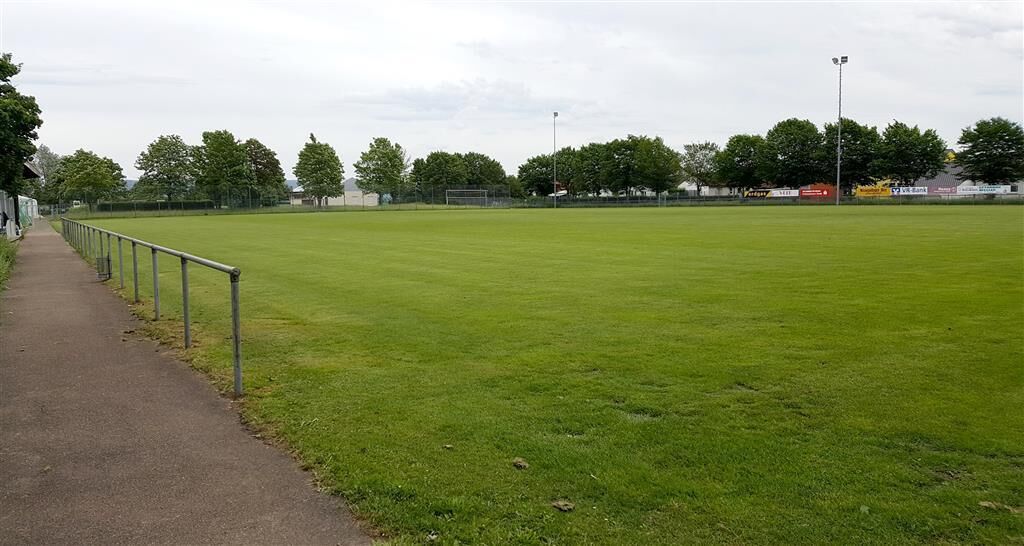 Een groot, open grasveld met een verharde wandelpad aan één kant.