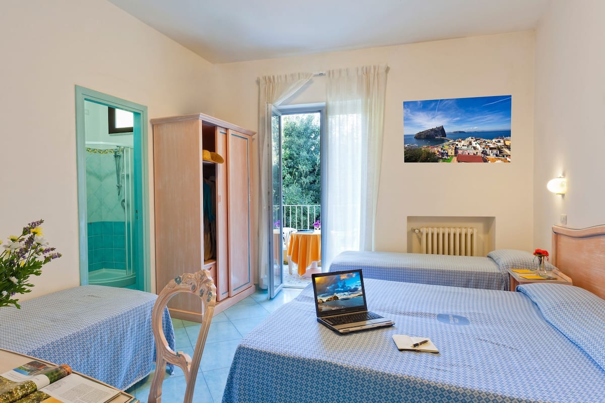 Habitación de hotel con dos camas, baño con ducha y vista al mar, además de un cuadro en la pared.