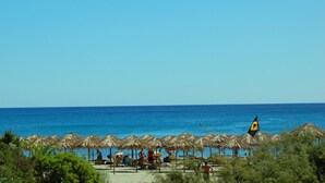 A beach with thatched umbrellas and a flag. - Villaggio Porto Corallo (Villaputzu)