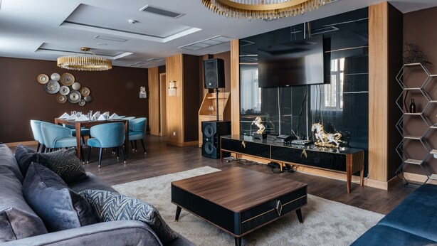 A modern living room with a sofa, coffee table, and a TV. There is a dining area with chairs and a table. - Ramada by Wyndham Astana (Astana)