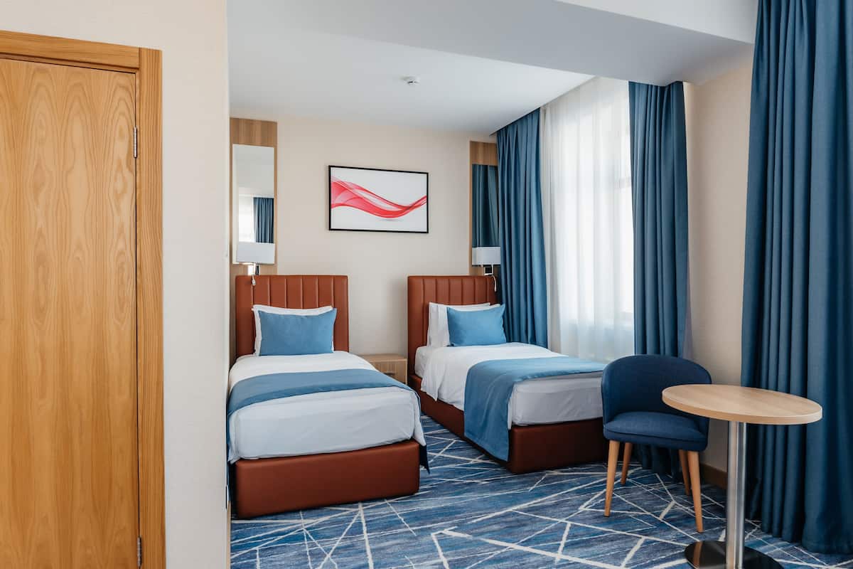 Une chambre d’hôtel avec deux lits, une petite table et une chaise.