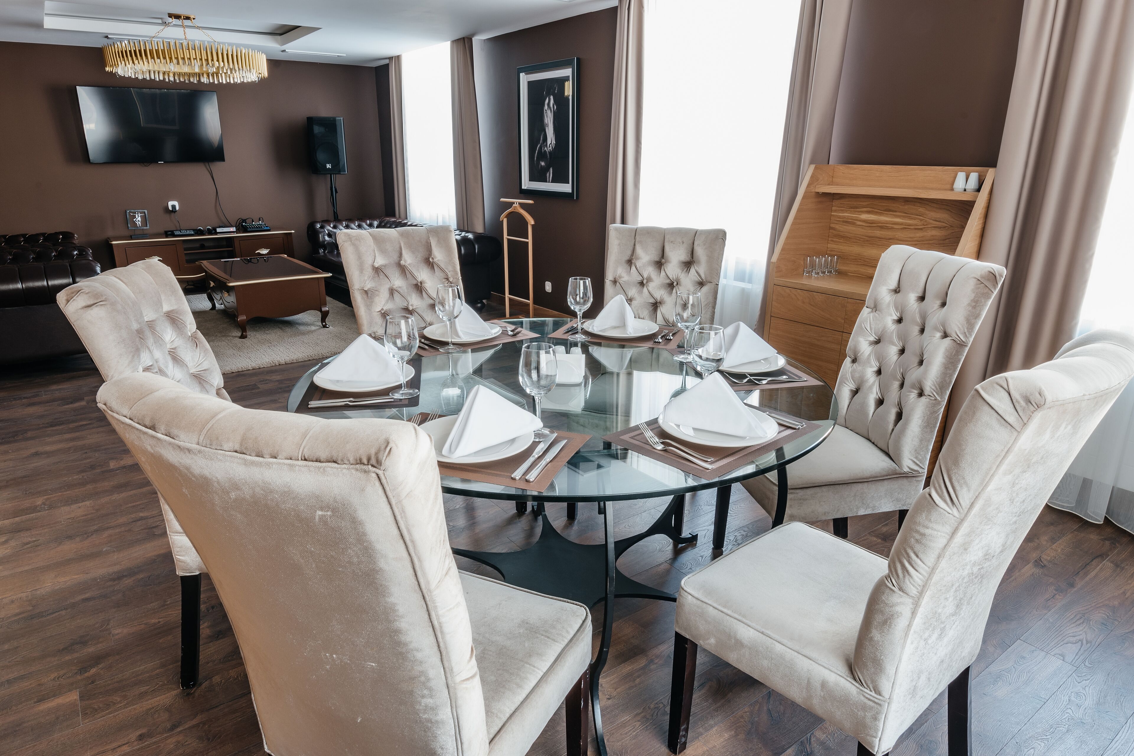 Un comedor con una mesa redonda de cristal dispuesta para seis personas, rodeada de sillas capitonadas.