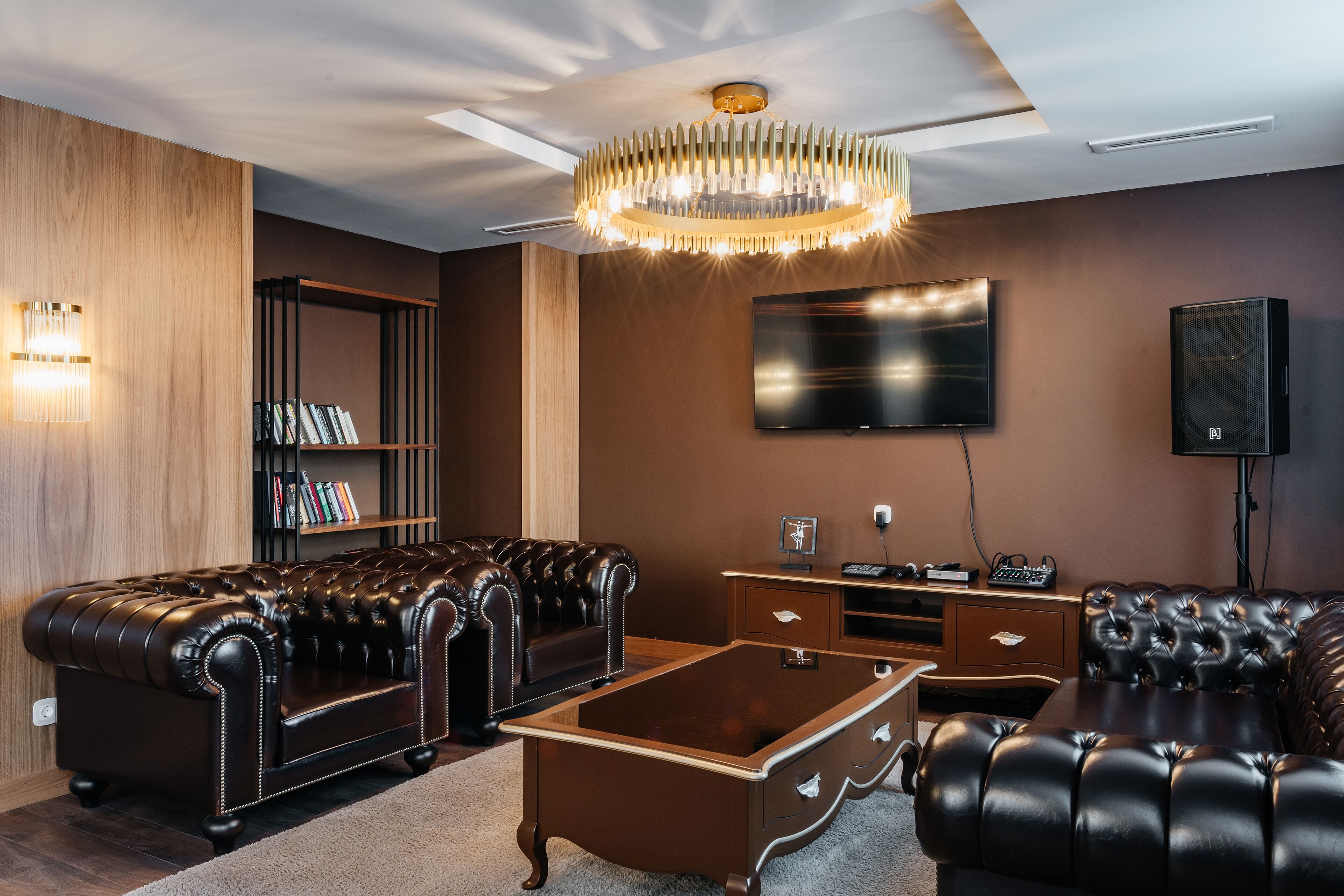 A modern living room with leather sofas, a coffee table, a TV, and a bookshelf.