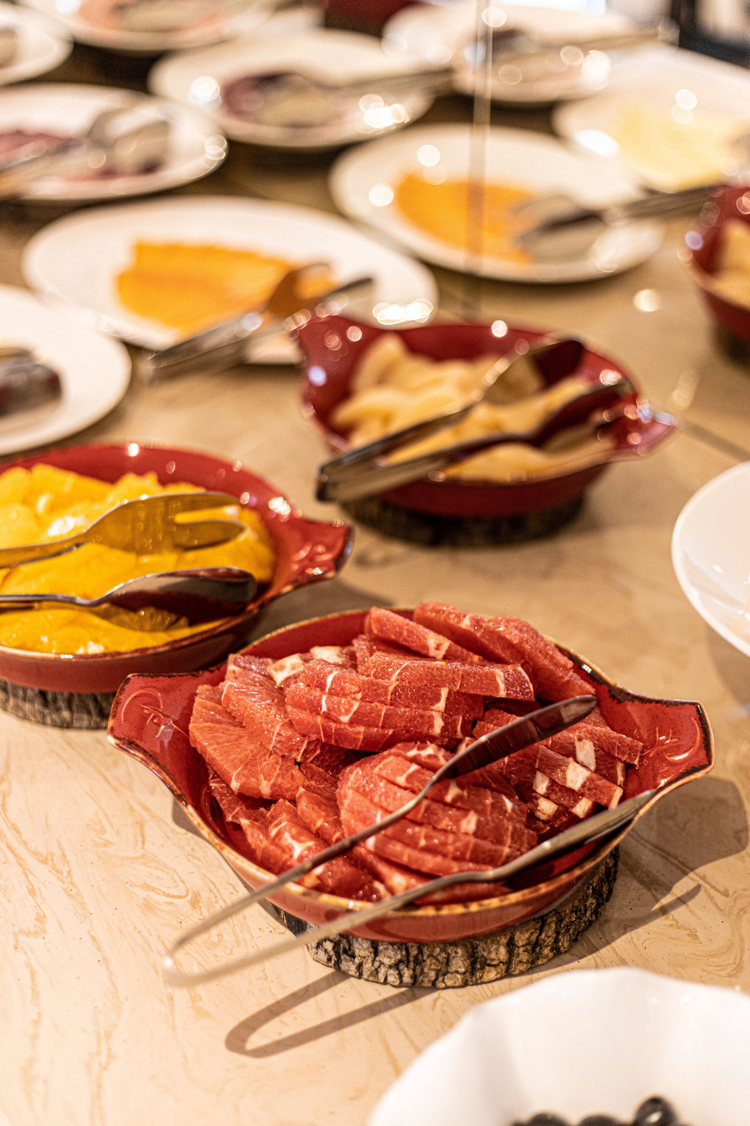 Una mesa de buffet con diferentes platos, incluyendo un bol de carne en rodajas y un bol de comida amarilla.
