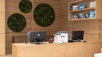 A reception desk with two HP monitors, a printer, and a bookshelf with books and a magazine.