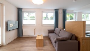 Ein modernes Wohnzimmer mit einer Couch, einem Couchtisch und einem an der Wand befestigten Fernseher.