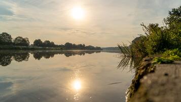 A calm lake with a clear reflection of the sky and trees, surrounded by greenery.
