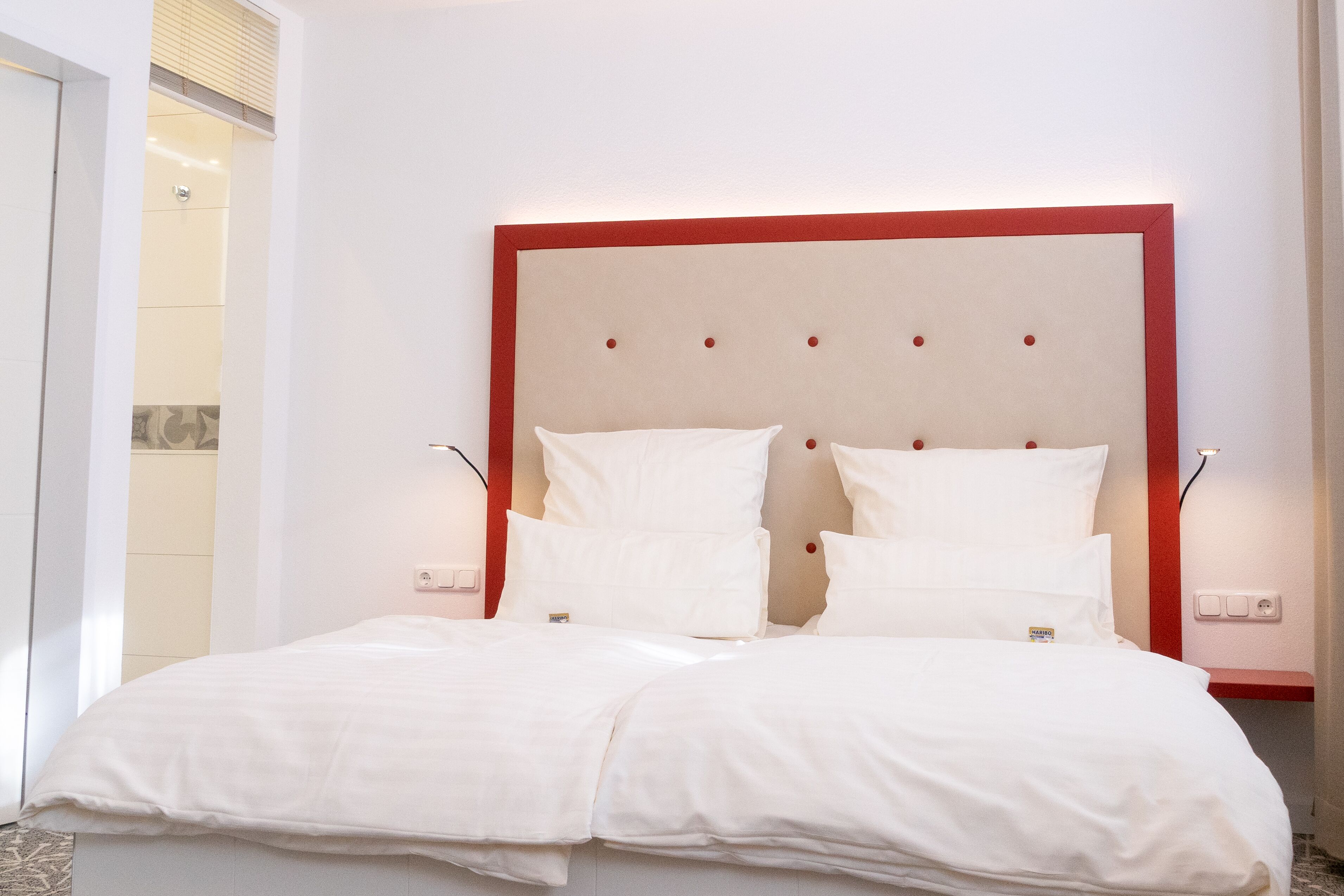 Una cama doble con cabecera roja en una habitación de hotel.