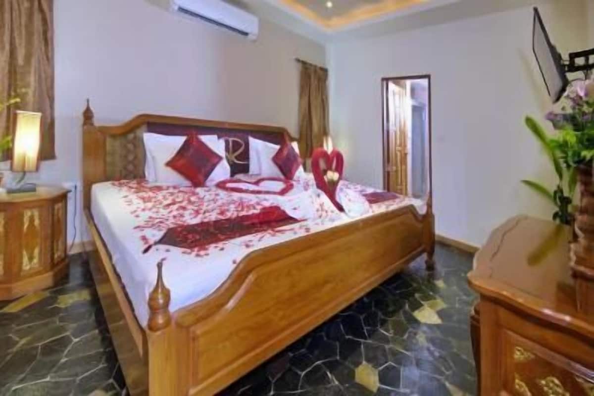 Um quarto com uma cama de madeira, mesa de cabeceira, espelho e planta em vaso.