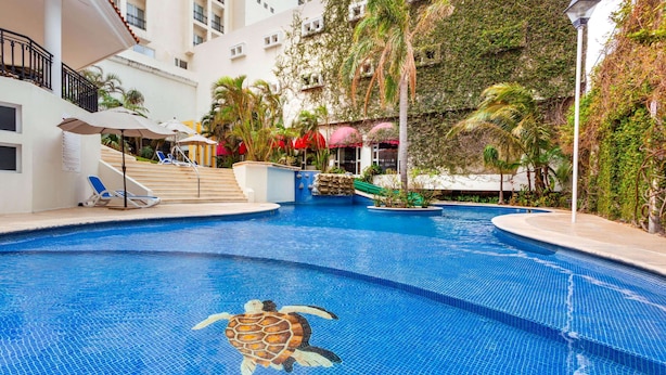 A swimming pool with a turtle mosaic, surrounded by palm trees and a building with balconies. - Ramada Plaza by Wyndham Veracruz Boca del Rio (Boca del Río)