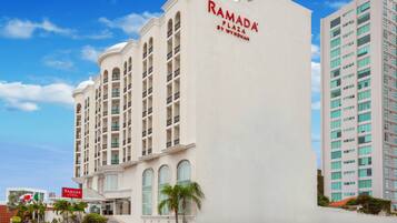 Un hotel de varios pisos con un cartel llamativo que dice "RAMADA PLAZA BY WYNDHAM".