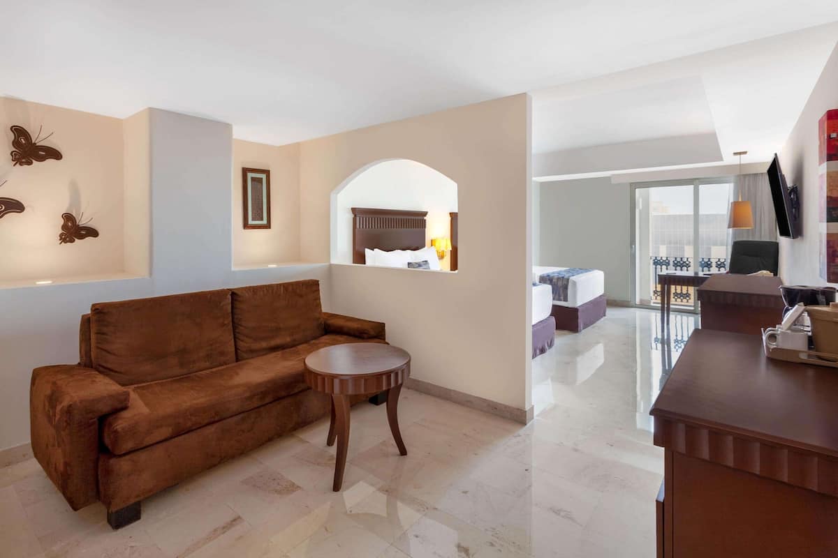 A modern living room with a brown sofa, a small round table, and a TV mounted on the wall.