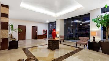 Un vestíbulo con una mesa redonda central, zona de estar y mostrador de recepción.