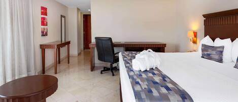 A hotel room with a large bed, a desk, a chair, and a small table.