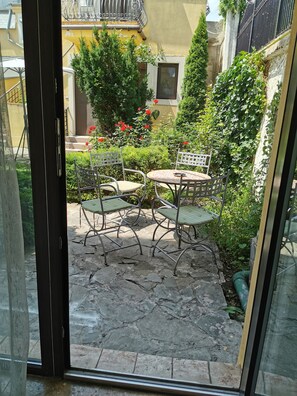 A courtyard with a stone floor, metal chairs, and a table.