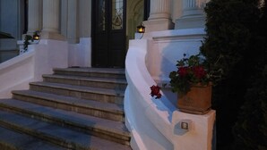 Una entrada imponente con una puerta negra, columnas blancas y una escalera que conduce a la entrada.