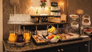 Disposición de bufé con diversas opciones de comida y bebidas, como frutas, panes y jugos.