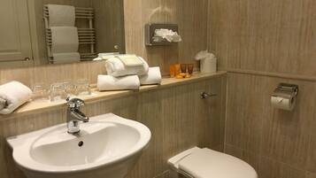 A bathroom with a sink, toilet, towel rack, and a shelf with toiletries.