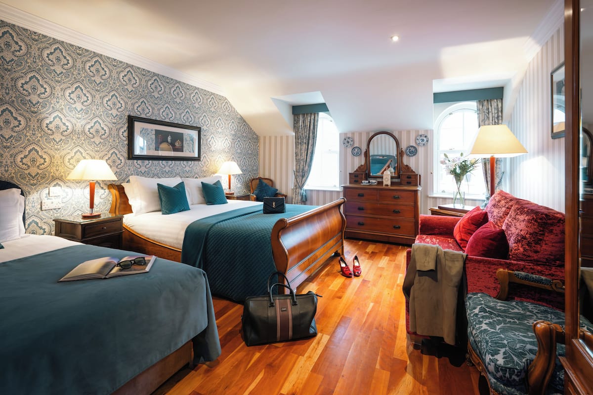 Habitación de hotel con dos camas, un aparador, un sofá rojo y un espejo.
