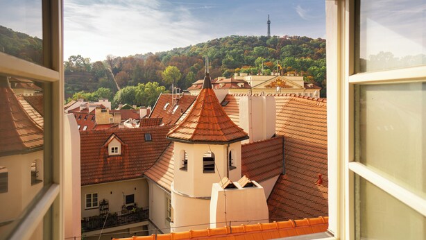A view from a window overlooking a town with traditional buildings and a hill in the background. - Hotel Golden Key Prague (Prague)