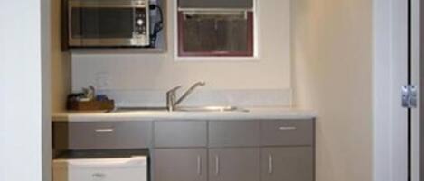 A compact kitchen with a microwave, refrigerator, and cabinets.