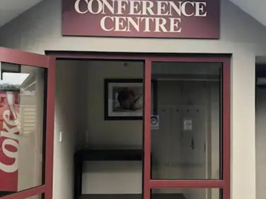 A building with a sign reading "Conference Centre" above a glass door.