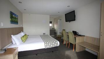 Una habitación de hotel con cama, escritorio, silla y televisor.