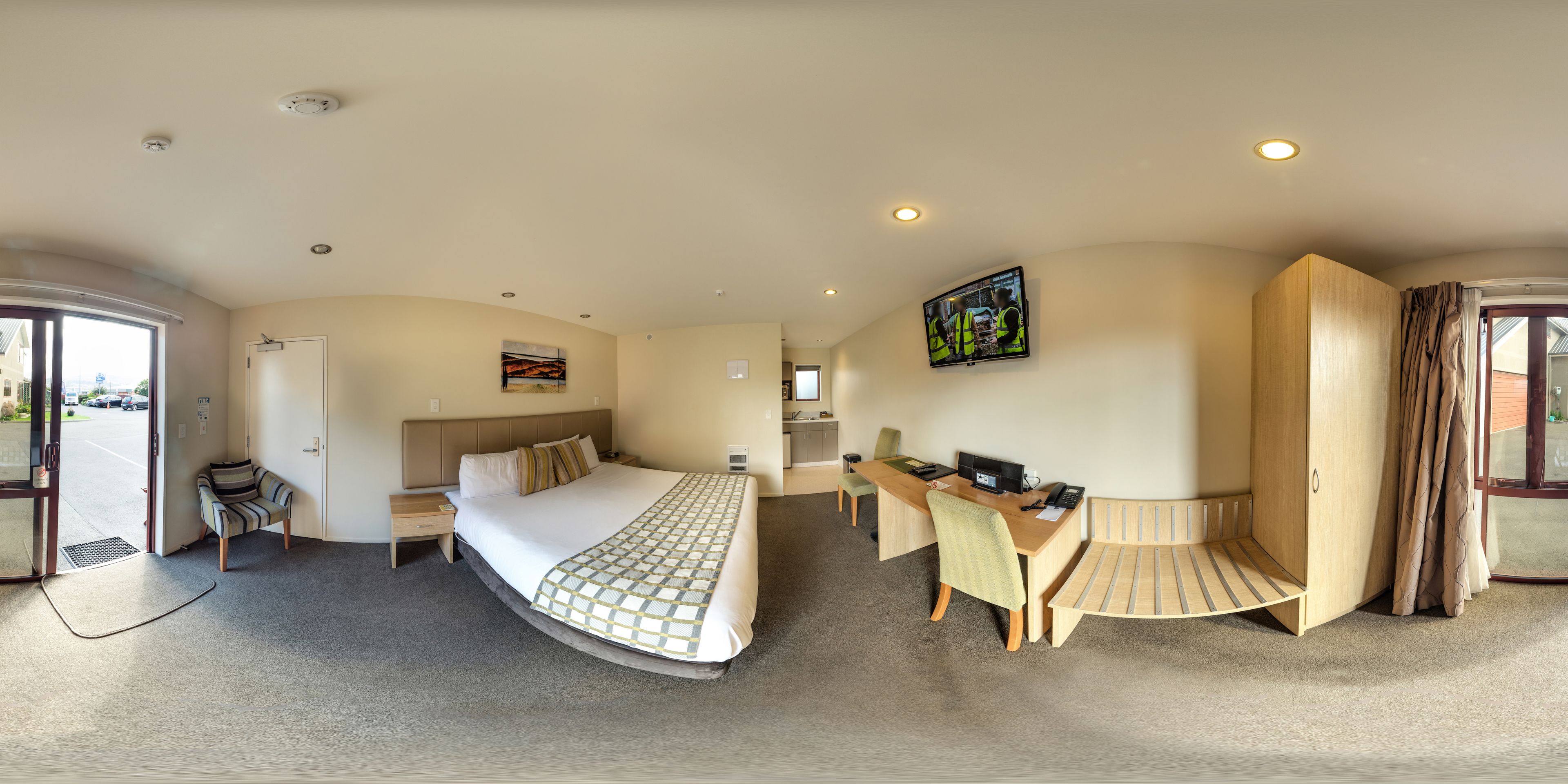 A modern hotel room with a bed, desk, and seating area.