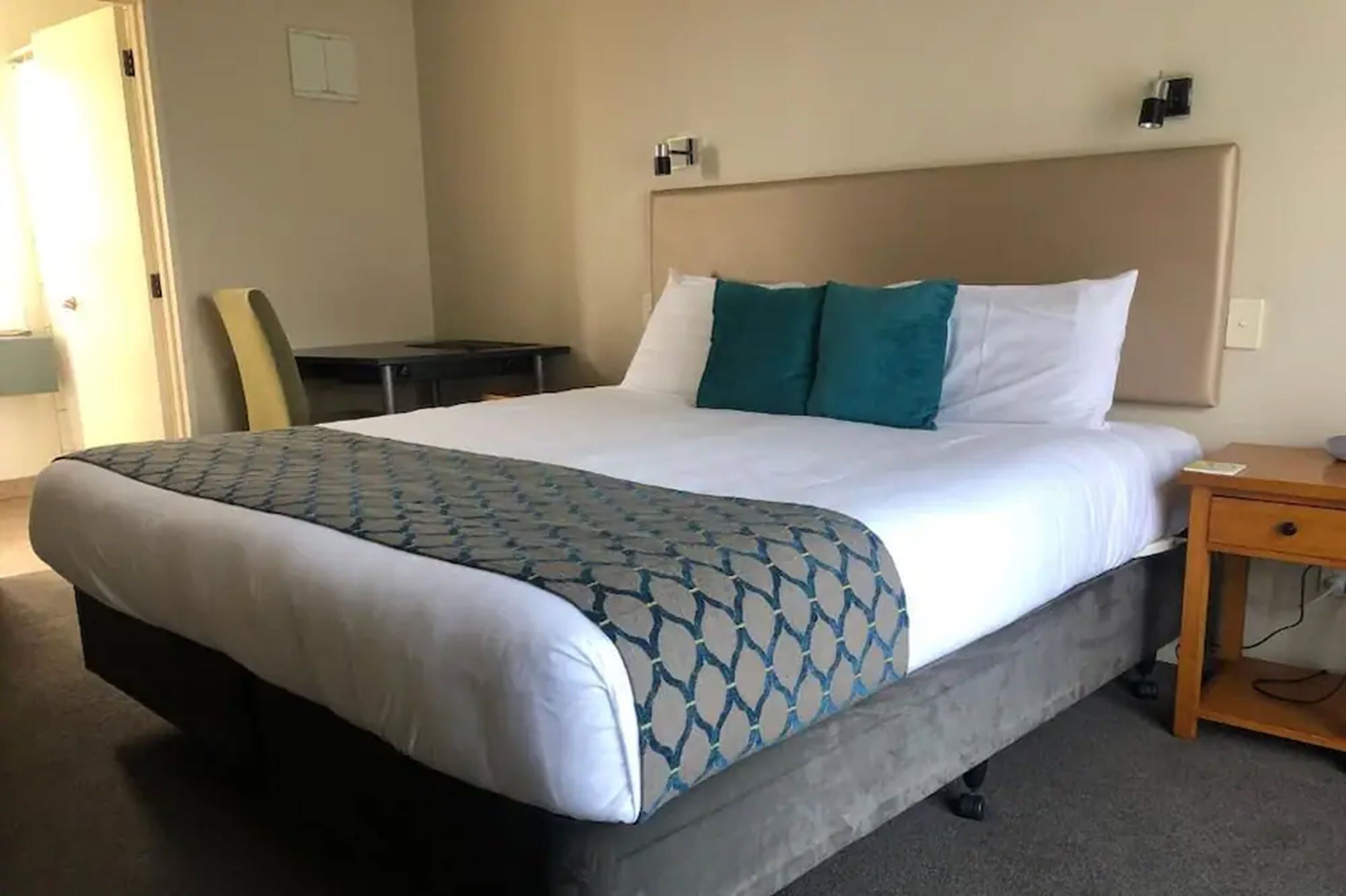 A hotel room with a bed, a desk, and a chair.
