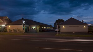 A hotel with a large parking lot, a covered outdoor area, and a building with a sign that reads "Hygiene Motor Lodge". - Hygate Motor Lodge (Hamilton)