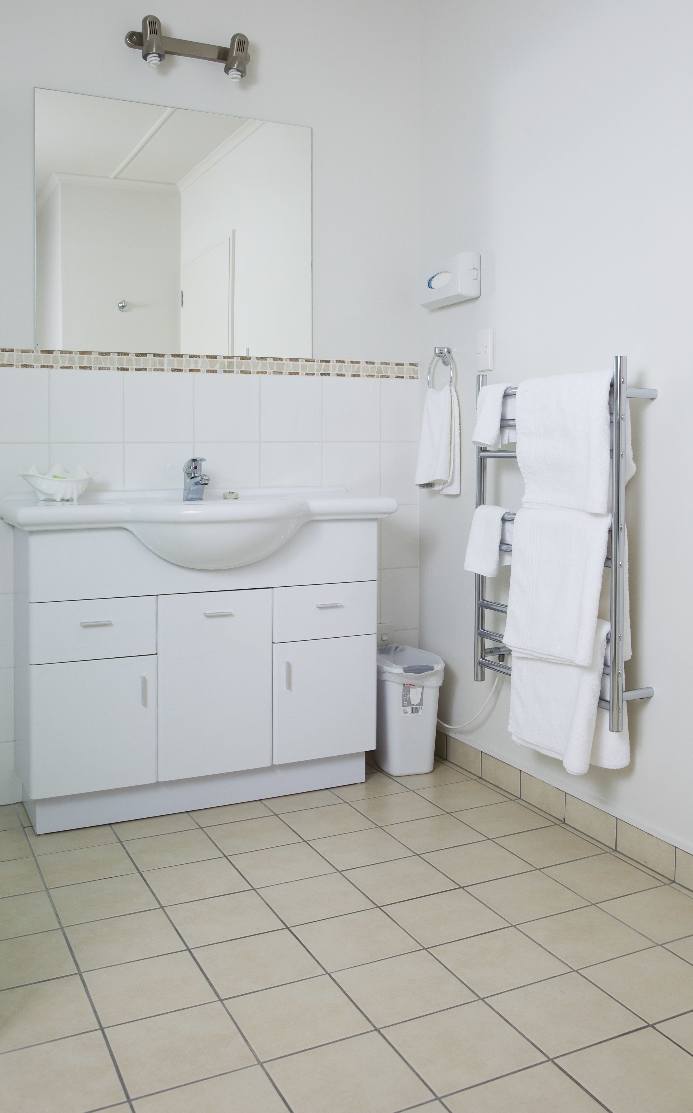 A bathroom with a white sink, mirror, and towel rack.