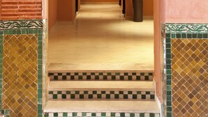 A corridor with a tiled floor, a framed picture on the wall, and a potted plant. - Mogador MENZAH (Marrakech)