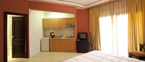Ein Hotelzimmer mit Bett, Fernseher, Küchenzeile und Badezimmer.