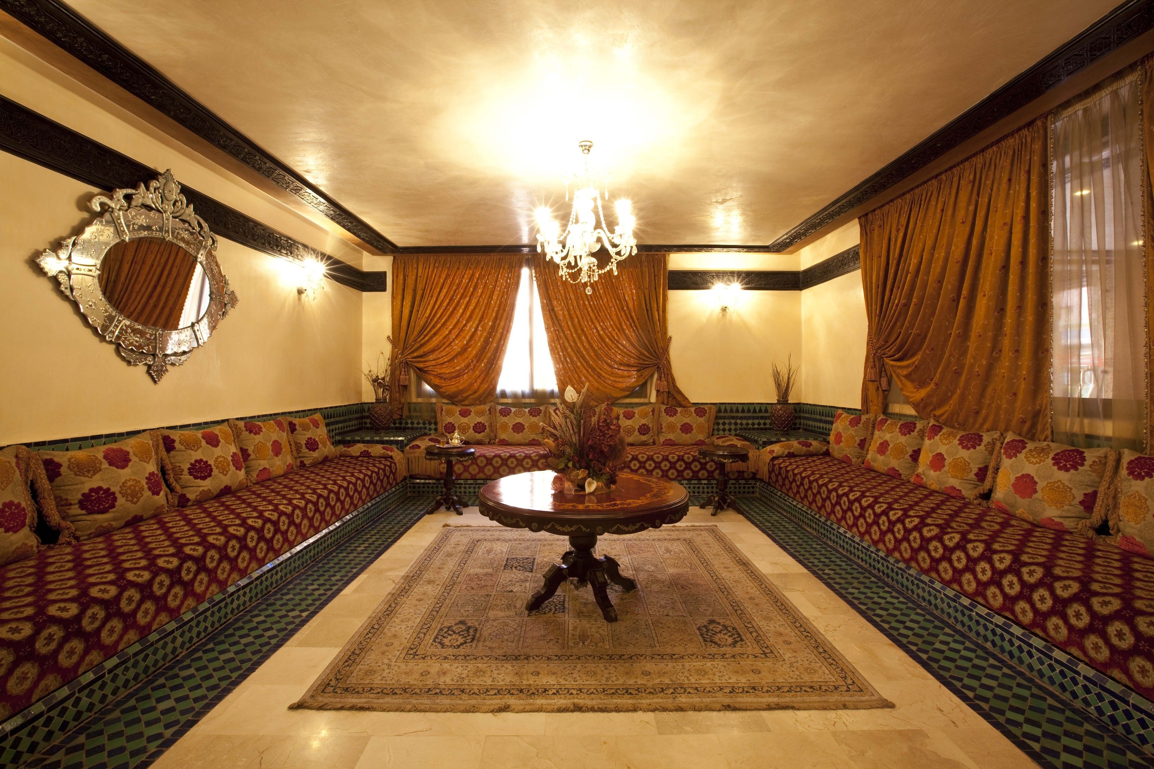 A traditional room with a central round table, patterned sofas, and a decorative mirror.