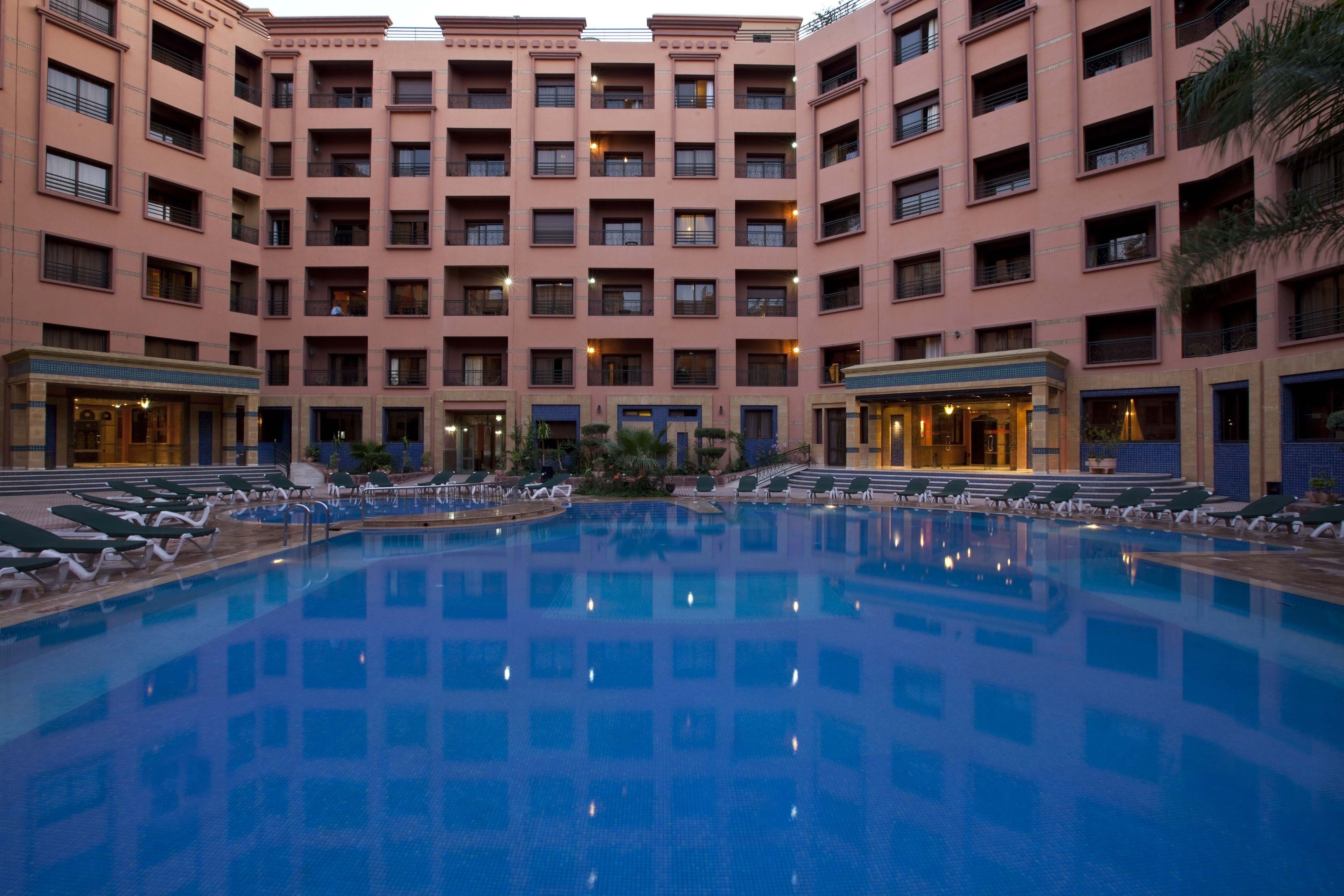 A large indoor swimming pool surrounded by multiple floors of a hotel with balconies and a central courtyard.