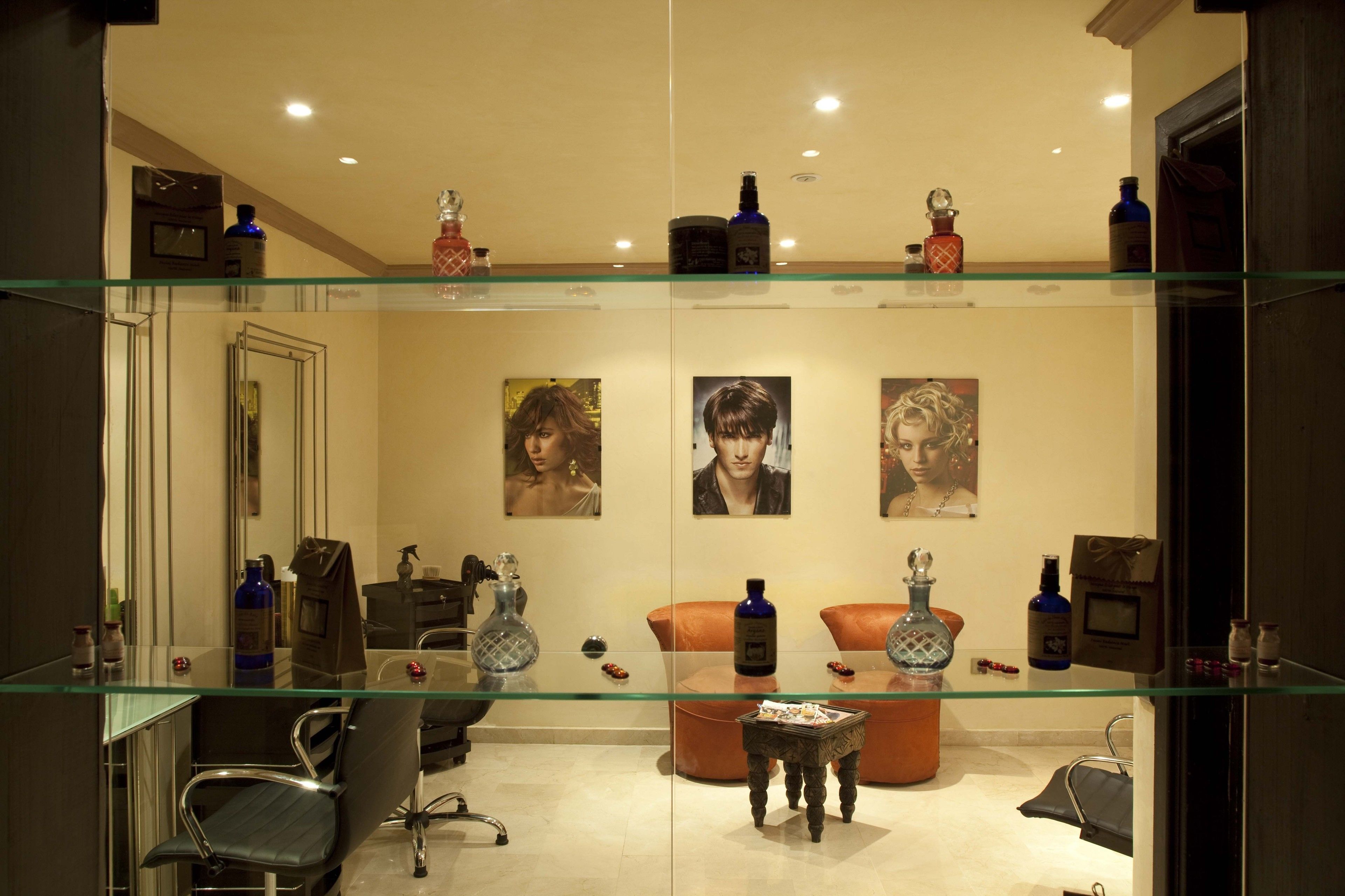 A modern bathroom with glass shelves, a mirror, a chair, and decorative items.