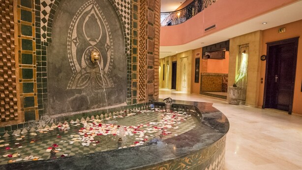 A marble fountain with rose petals in a hotel lobby. - Mogador MENZAH (Marrakech)