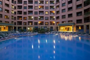 Een buitenzwembad, parasols bij het zwembad en ligstoelen