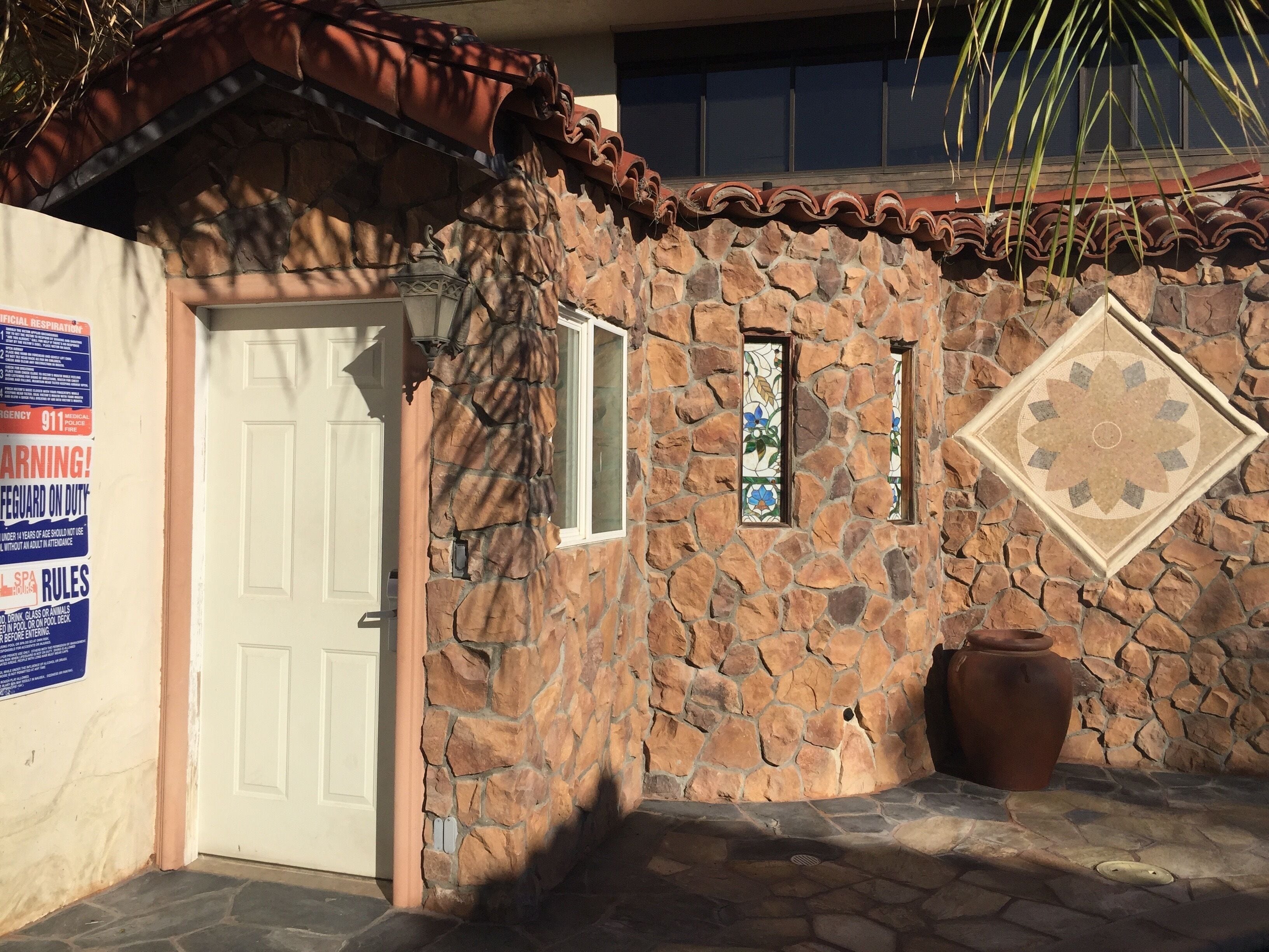A stone building with a white door, a small window, and a decorative tile.
