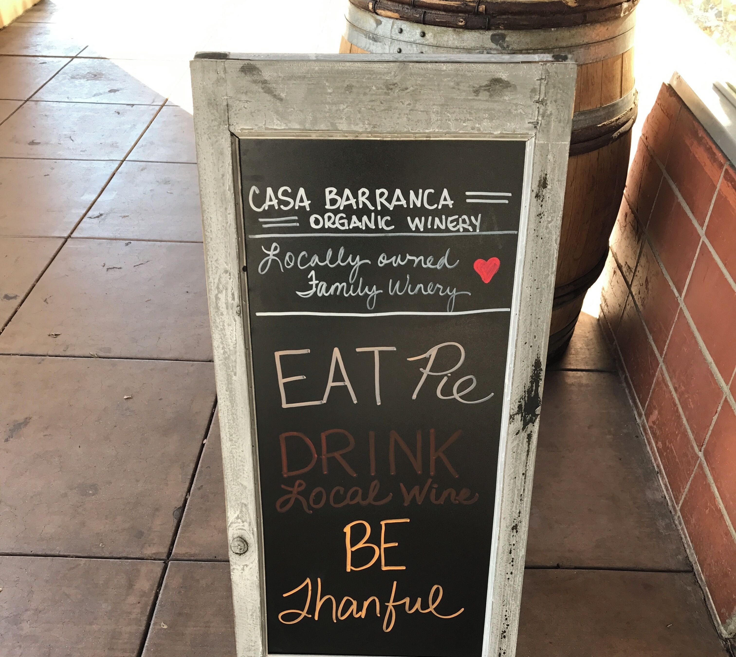 Una pizarra anuncia Casa Barranca Organic Winery, con vino local, comida y un negocio familiar.